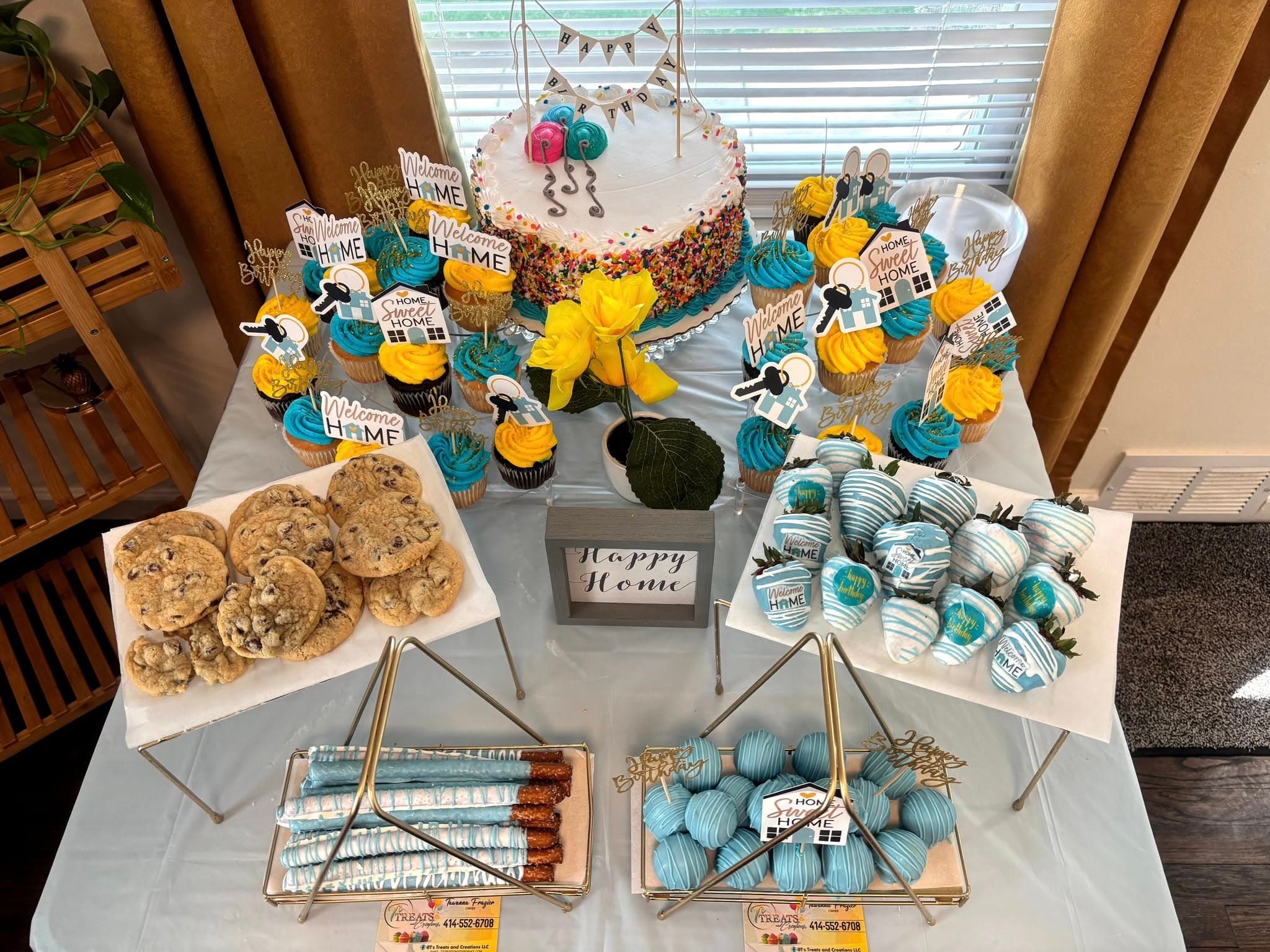 Dessert table with a sprinkle cake, blue and yellow cupcakes, cookies, and blue chocolate treats.