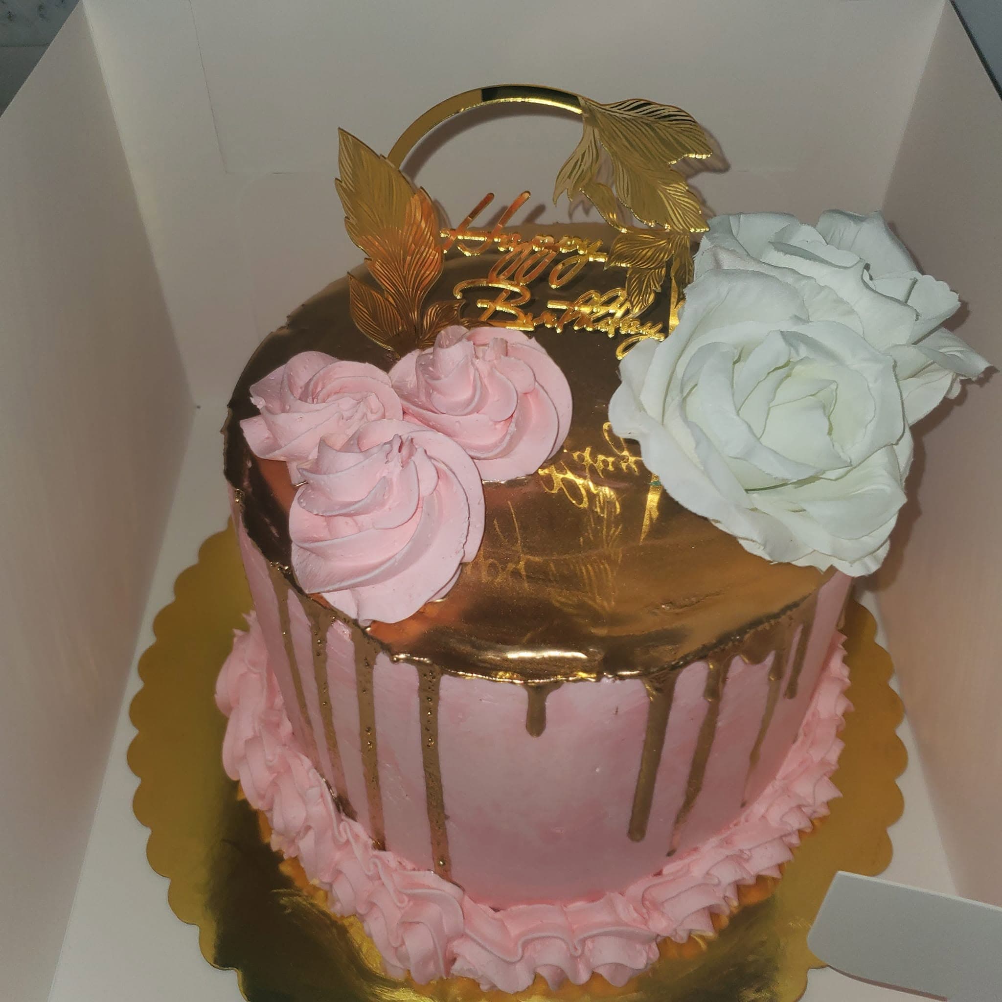 Elegant pink cake with gold drip, topped with pink and white roses and gold birthday topper.