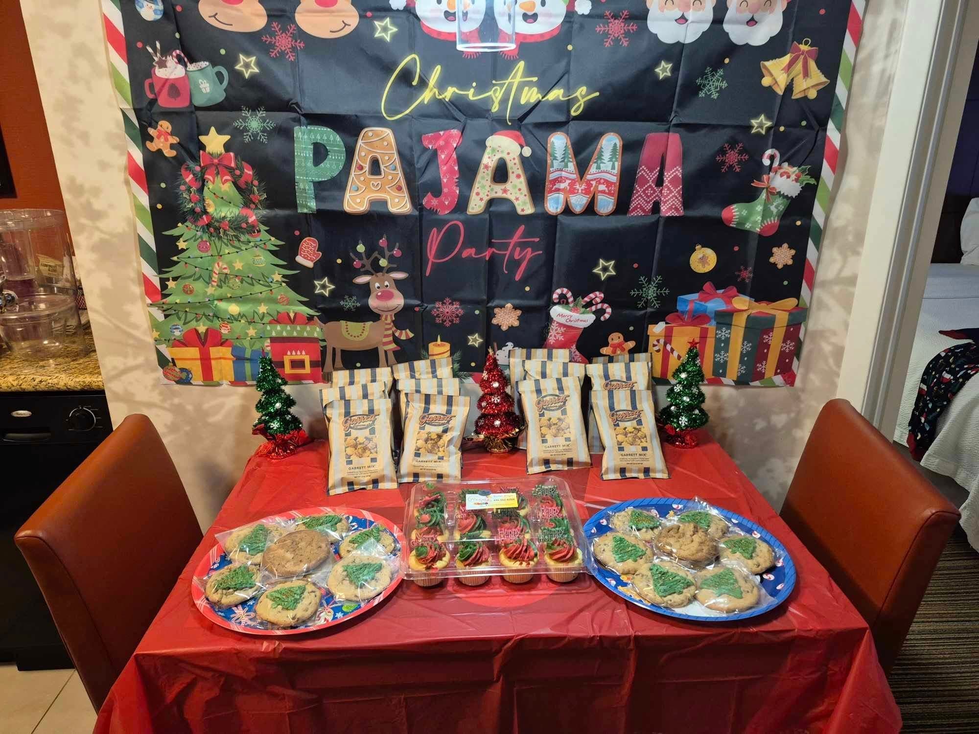 Christmas Pajama Party table featuring platters of cookies, cupcakes, and bags of popcorn.