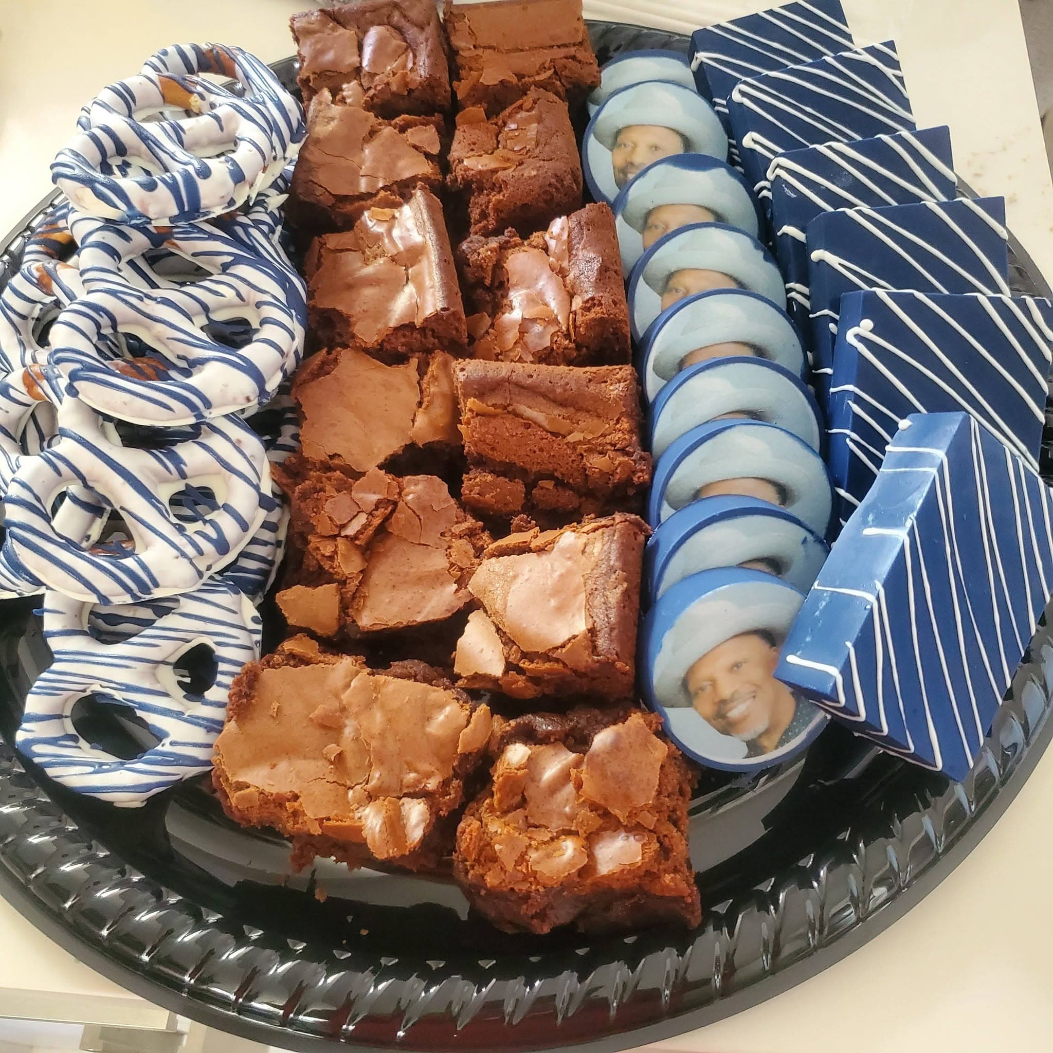 Dessert platter with chocolate brownies, blue and white drizzled pretzels, and custom photo cookies.