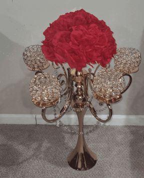Gold candelabra centerpiece with red roses and four crystal-beaded globes on curved arms.